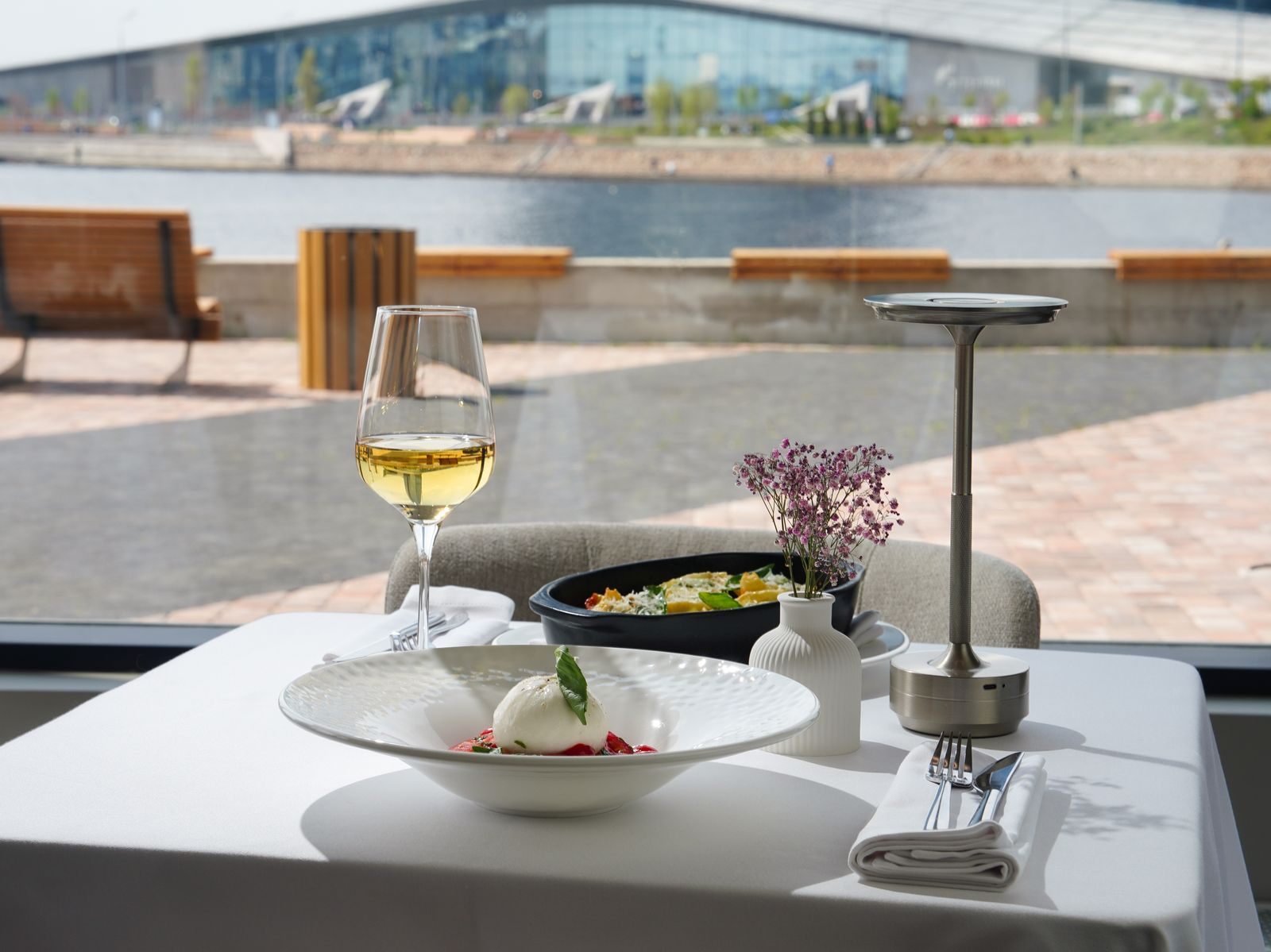 Table set with white wine and a plated dish on a waterfront terrace