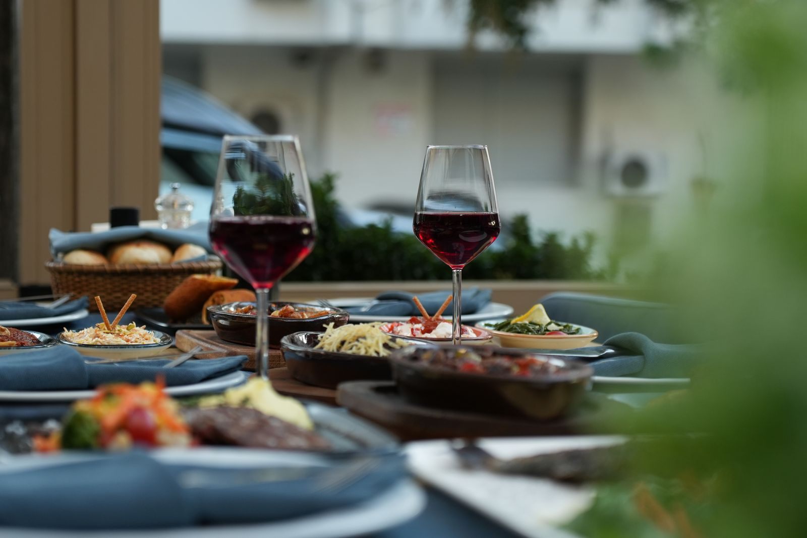 Glasses of red wine and plates of food on a set table, the kind of meal covered on all inclusive river cruises